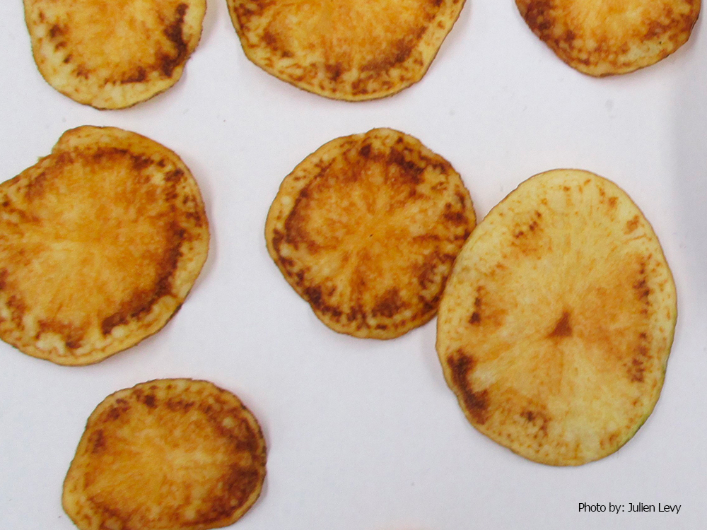 Potato with Zebra Chip symptoms, showing a yellow interior with dark spots and brown skin.