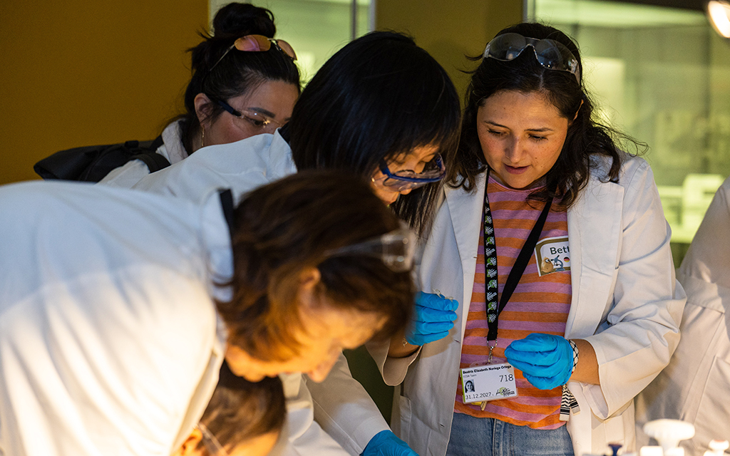 Participants in lab coats and gloves examining samples during a PataFEST citizen science activity.