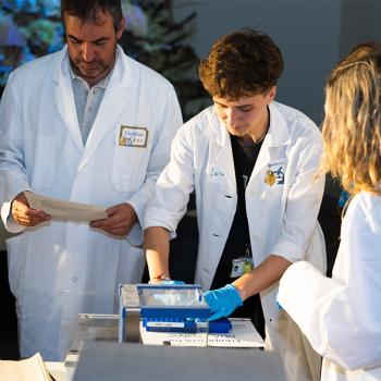 Participants in lab coats working with DNA analysis equipment at a PATAFEST science workshop.